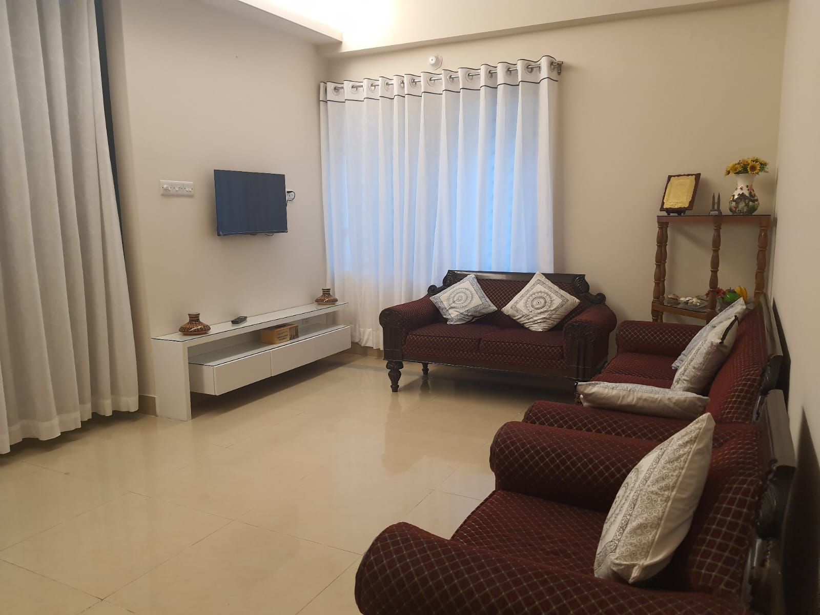 A living room with a sofa set, a television, and a small table with decorative items.