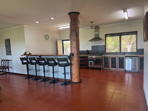 Cuina àmplia amb una illa central, tamborets de bar, fornet i rentaplats.