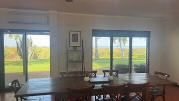 A dining area with a large table and chairs, a ceiling fan, and a view of a landscape through glass doors.