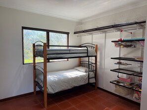 A bunk bed with a window, a shelving unit with storage bins, and a tiled floor.