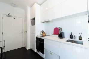 A modern kitchen with white cabinetry, a black oven, and a stainless steel sink. - Boutique Designer Studio at Shed 19 (Auckland)