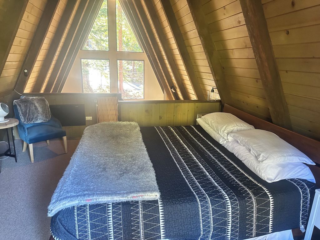 A room with a bed, a chair, and a window.