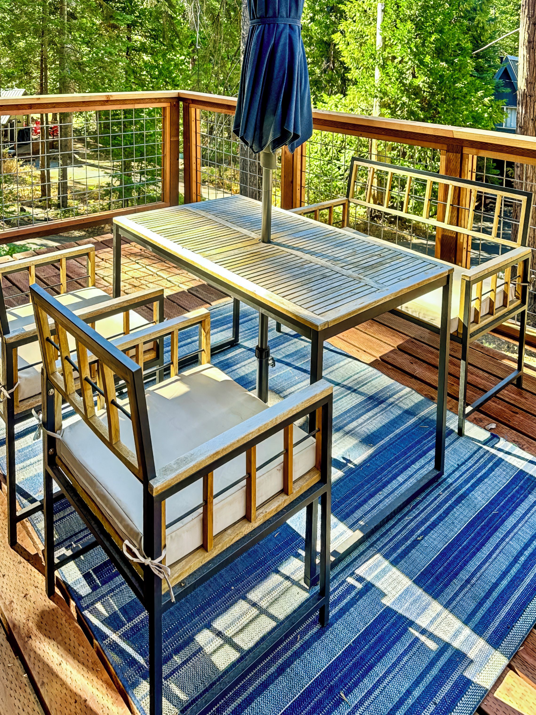 An outdoor deck with a table and chairs, surrounded by a wooden railing.