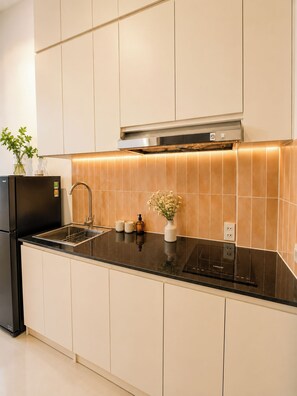A modern kitchen with a black countertop, stainless steel appliances, and a tiled backsplash. - 4-bedroom house in tranquil Thành phố Hồ Chí Minh with AC (Thành phố Hồ Chí Minh)