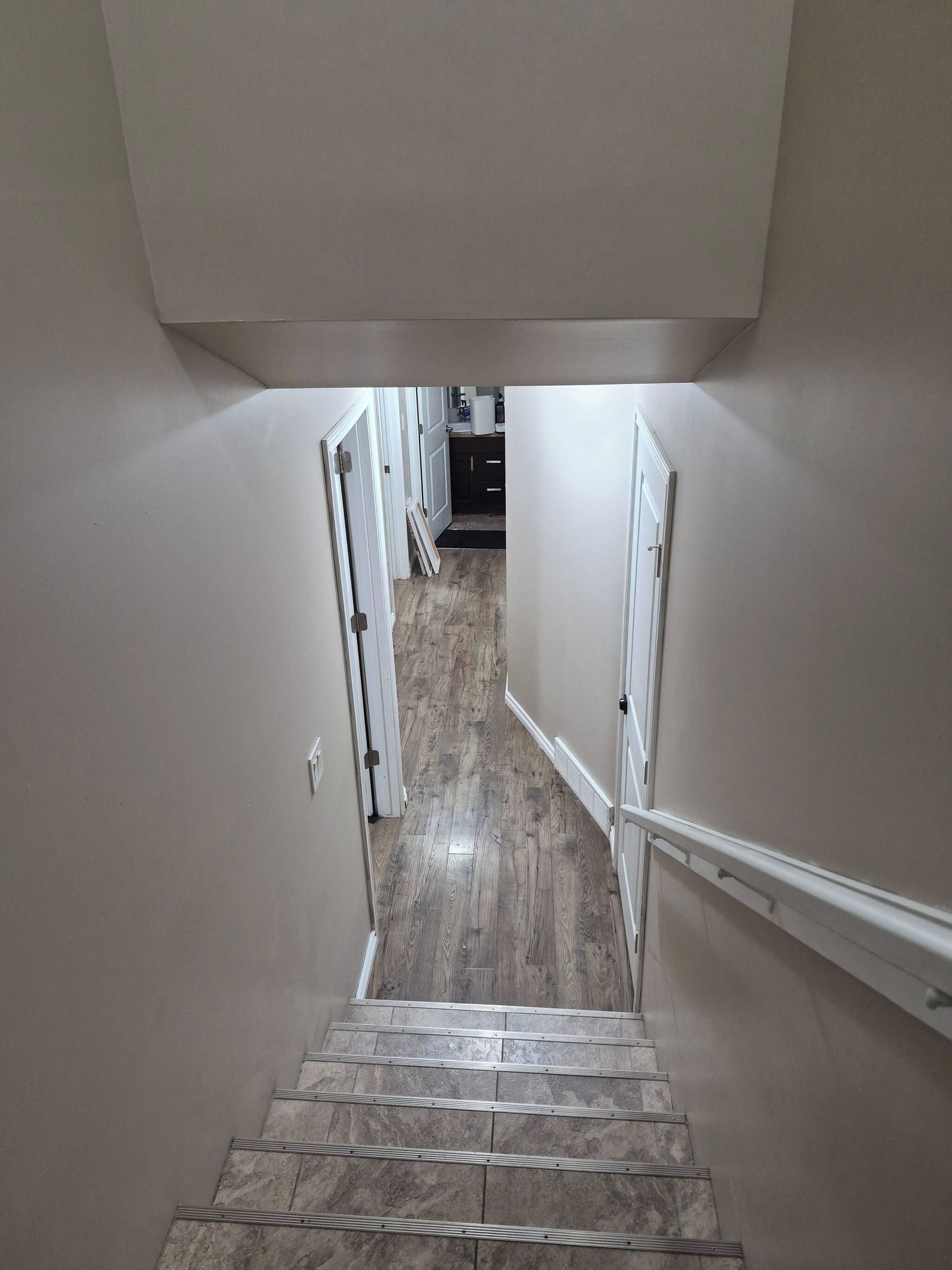 A staircase leading to a landing with a kitchen area in the background.