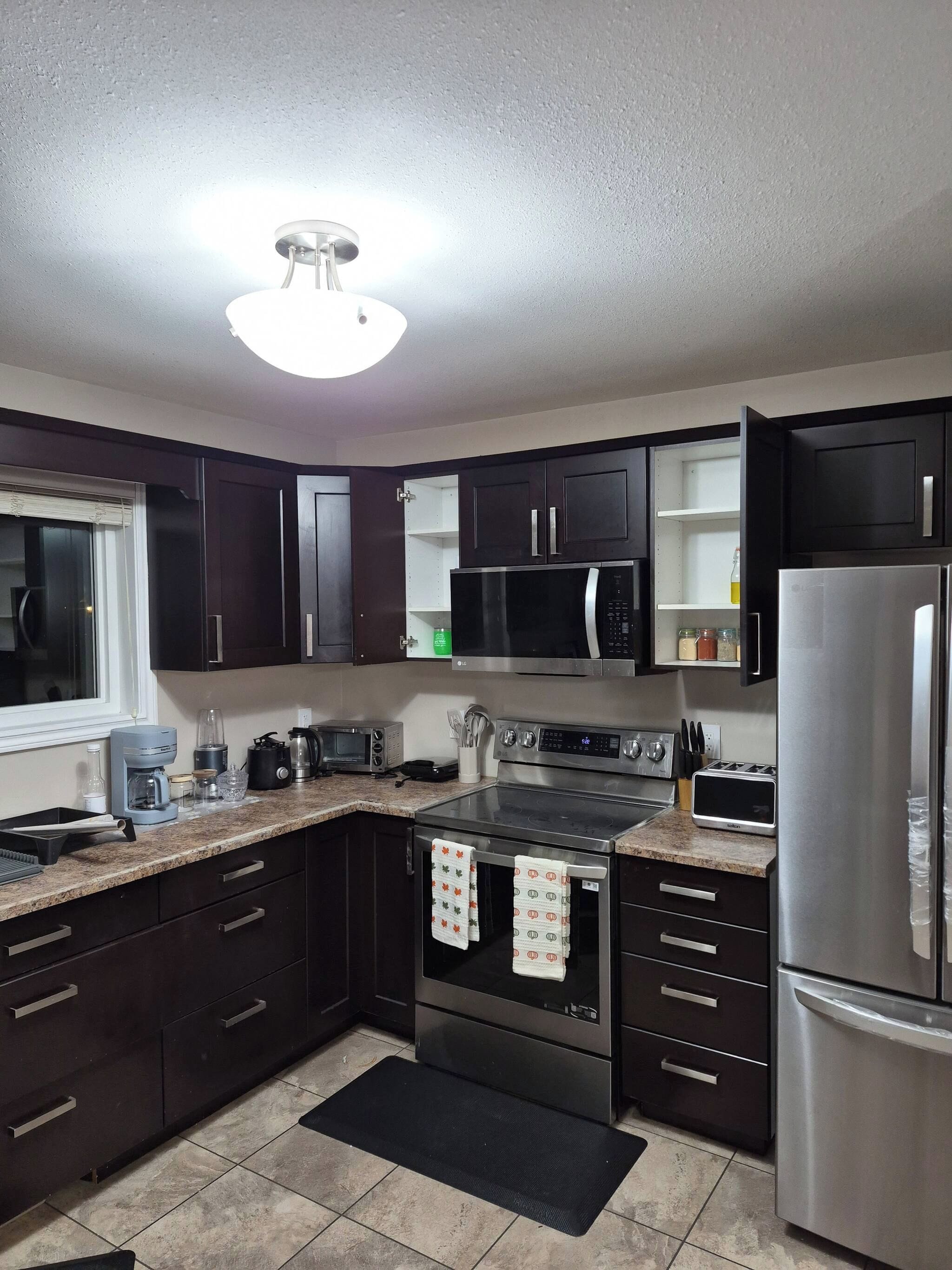 A modern kitchen with dark cabinets, stainless steel appliances, and a granite countertop.