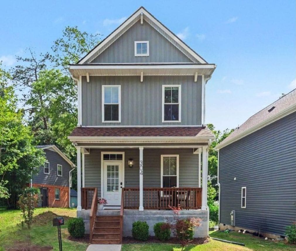 Charming two-story home with a welcoming front porch and beautiful surroundings.