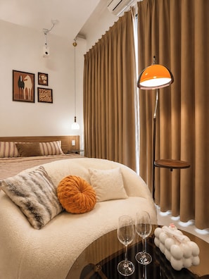 Et hotelværelse med en seng, et natbord med glas, en lampe og gardiner.