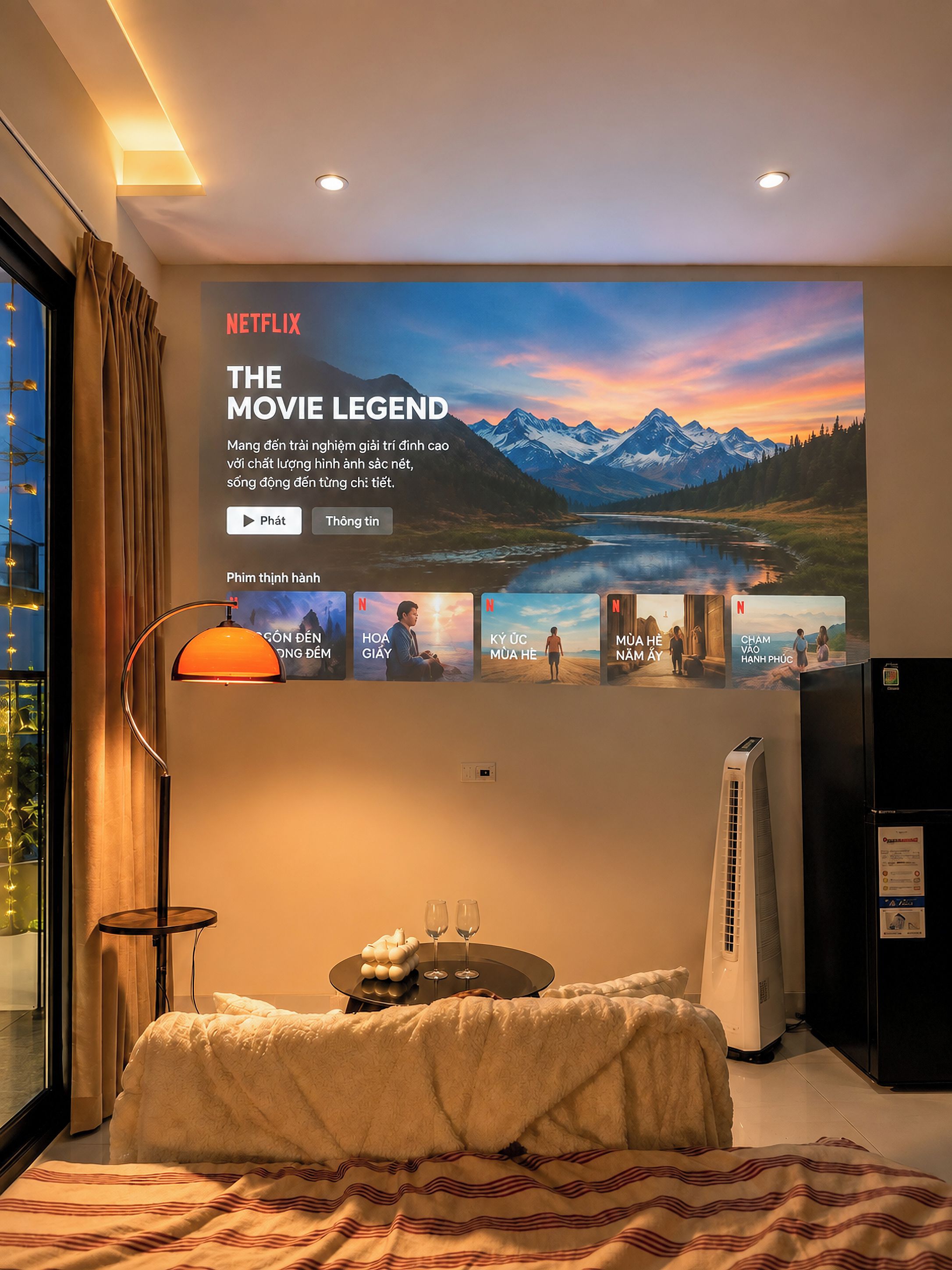 A hotel room with a large poster of 'The Movie Legend' on the wall, a bed with a striped blanket, a bedside table with glasses, and a standing heater.