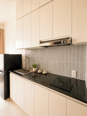 A modern kitchen with white cabinets, a black countertop, a stainless steel range hood, and a tiled backsplash. - Cozy 1-bedroom house in tranquil Thành phố Hồ Chí Minh with AC - 201 (Thành phố Hồ Chí Minh)