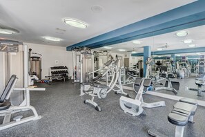 A gym with various exercise equipment, a mirrored wall, and a blue accent wall. - LUXE 2BR/2BA Retreat near TMC & NRG (Houston)