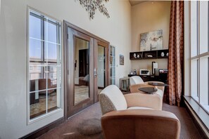 A hotel room with a sliding glass door leading to a balcony, a seating area with a table, and a desk with a computer and printer. - LUXE 2BR/2BA Retreat near TMC & NRG (Houston)