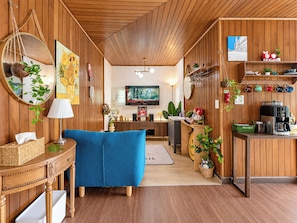 A cozy kitchen with wooden walls, a blue sofa, and a dining area with a table and chairs. - Spacious Family Villa with Private Terrace in Jong-ro / 3 queen bed n 1 bath (Seoul)
