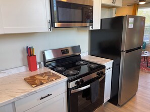 A modern kitchen with a stainless steel stove, black refrigerator, and white cabinets. - Heart of Tobin Hill! Walk to The Pearl, River Walk! King Bed, Pac-Man, Sleeps 4 (San Antonio)