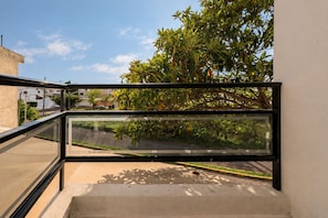 A modern balcony with a glass railing overlooking a street and greenery. - Family Home | Excellent Location | 5B 3BR 2.5BA (Durango)