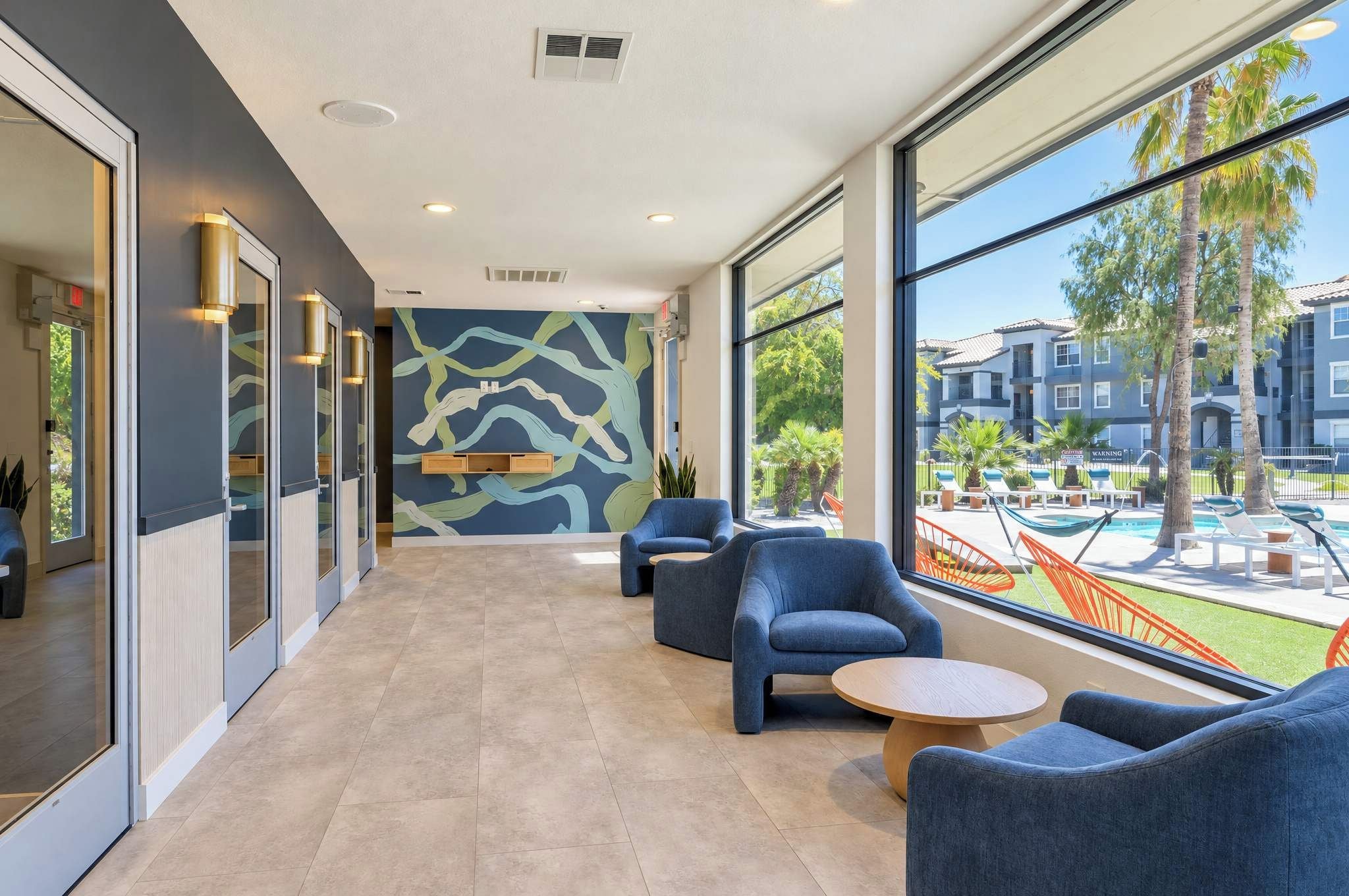 A modern lounge area with seating and a view of a pool and buildings.