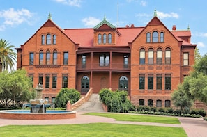 A large, two-story brick building with a symmetrical facade, a central entrance with a staircase, and a small fountain in the front courtyard. - Boulevard Stays Tempe 3BR 2BA near ASU, Pool, Gym (Tempe)