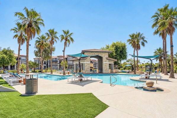 A resort with a swimming pool, lounge chairs, palm trees, and a building with a tiled roof. - Boulevard Stays Tempe 3BR 2BA near ASU, Pool, Gym (Tempe)