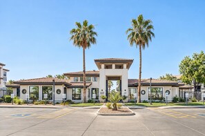 A building with a central entrance, surrounded by a parking lot and palm trees. - Boulevard Stays Tempe 2BR 2BA near ASU, Pool, Gym (Tempe)