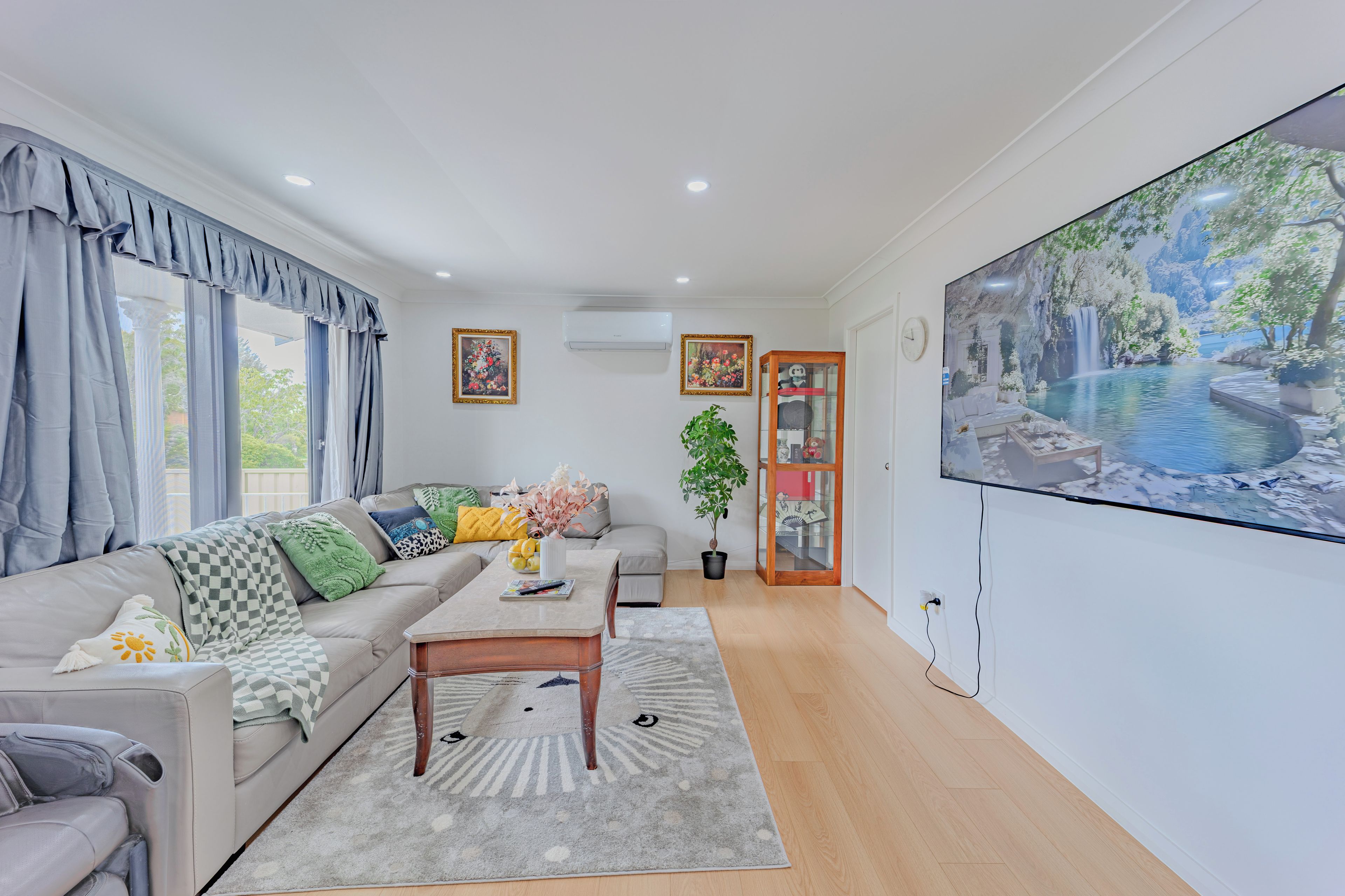 A modern living room with a sofa, coffee table, and a large TV screen displaying a nature scene.