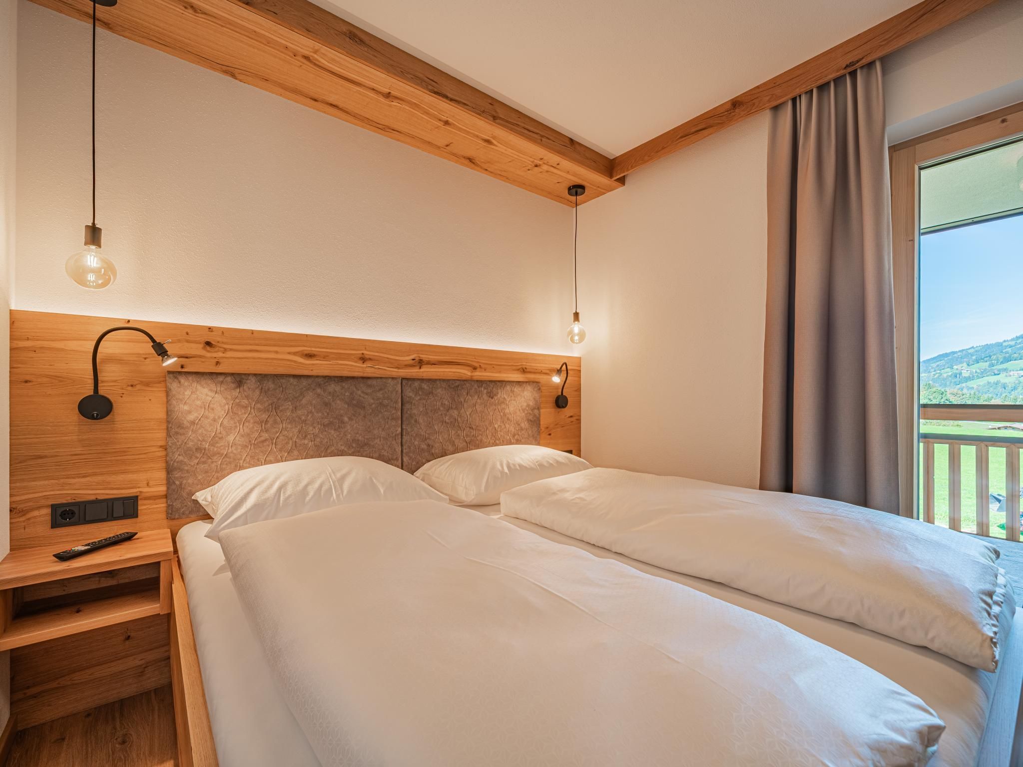 Ein Doppelbett mit Holz Kopfteil, Nachttischlampen und Blick auf einen Balkon.