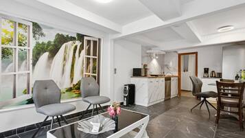 Ein modernes Interieur mit Essbereich, Küche und großem Fenster mit Blick auf einen Wasserfall.