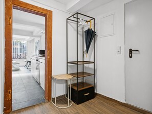 Ein Zimmer mit Holztür, weißer Wand, schwarzem Stauraum mit Regalen, einem kleinen runden Tisch und einer Tür mit Griff.