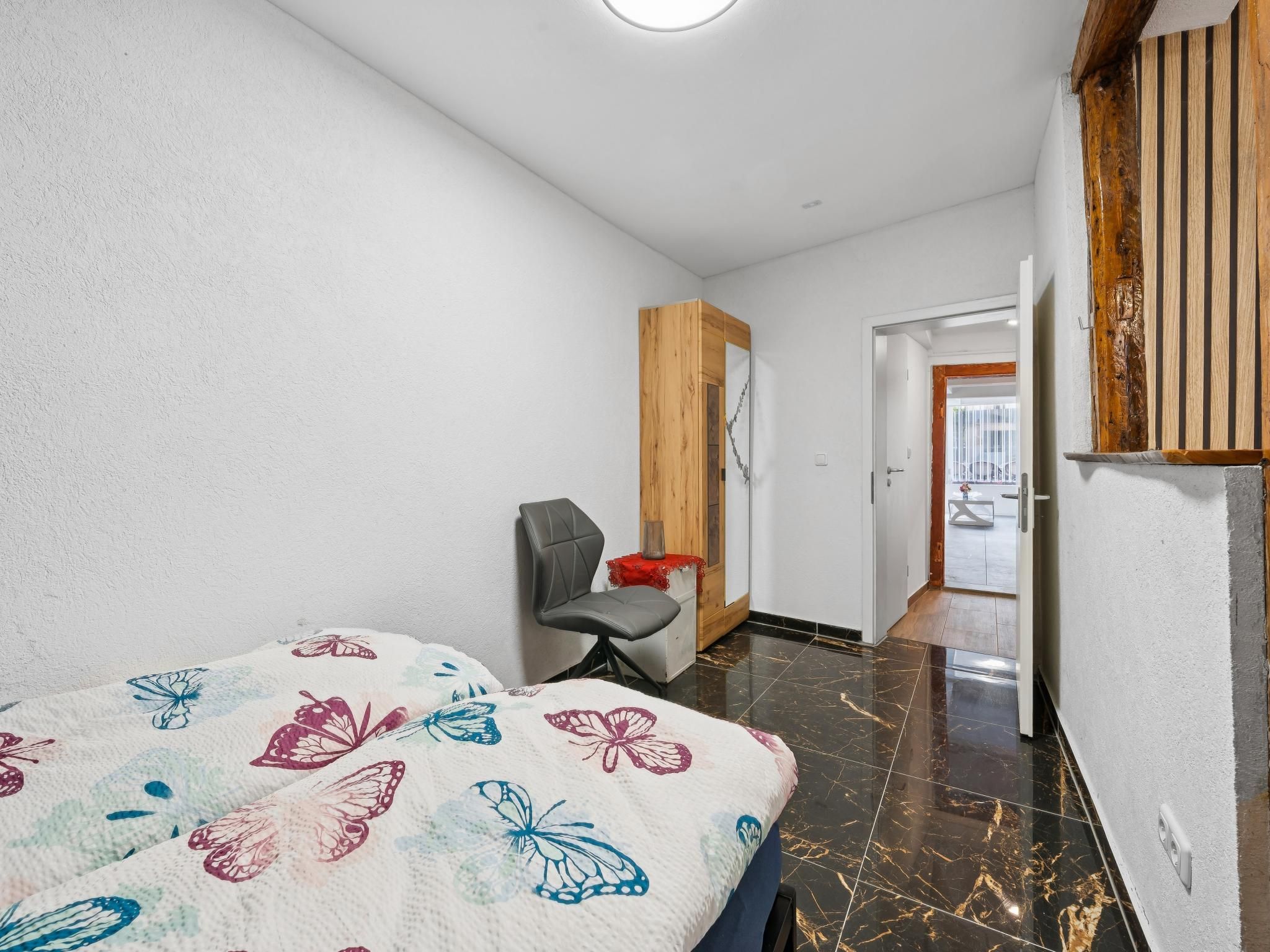 Ein Hotelzimmer mit Bett, Stuhl, Kleiderschrank und einer Tür zu einem Außenbereich.