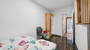 Ein Hotelzimmer mit Bett, Stuhl, Kleiderschrank und einer Tür zu einem Außenbereich.