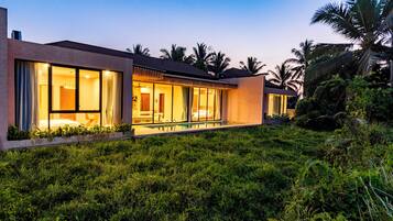 A modern building with large windows, a swimming pool, and lush greenery.