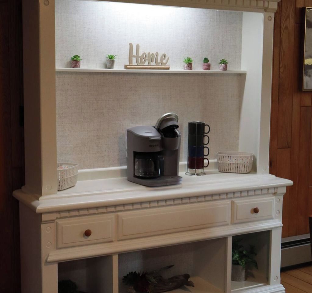 A kitchen counter with a coffee maker, a mug, and small potted plants.