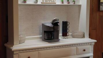 A kitchen counter with a coffee maker, a mug, and small potted plants.