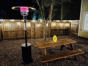 A wooden table and benches in a backyard with a patio heater and a lantern. - House 3-Bed 2,5-Bath FREE Parking - Nice Backyard (Spring)