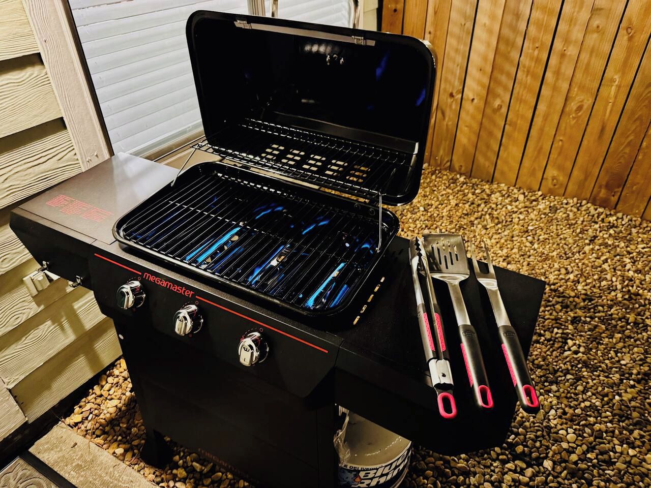 A portable barbecue grill with a control panel and a set of barbecue utensils.