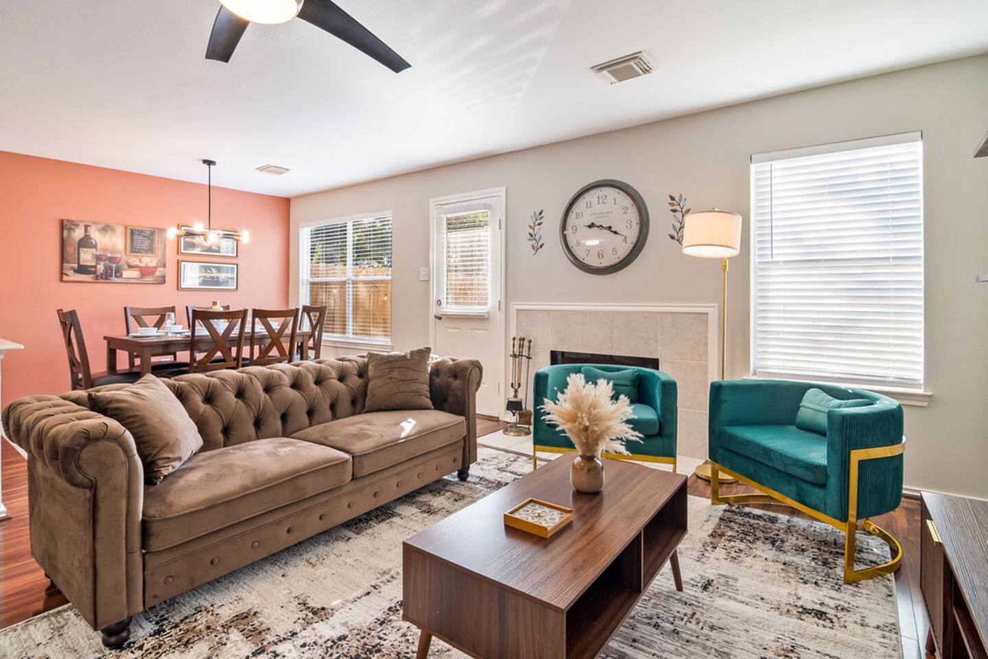 A living room with a brown sofa, teal armchairs, a coffee table, and a fireplace.