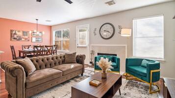 A living room with a brown sofa, teal armchairs, a coffee table, and a fireplace.