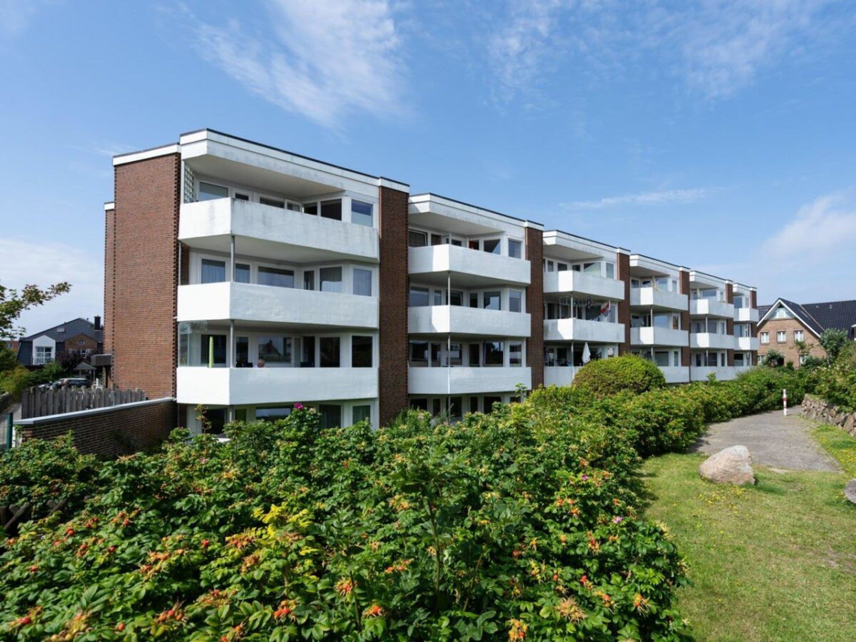 A multi-story residential building with a brick facade and white balconies.