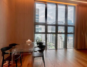 A modern room with a large window, a glass table, and a view of buildings. -  5 Mins to Coex - Gangnam - Two Bedroom Apartment  -  Samsung Station (Seoul)