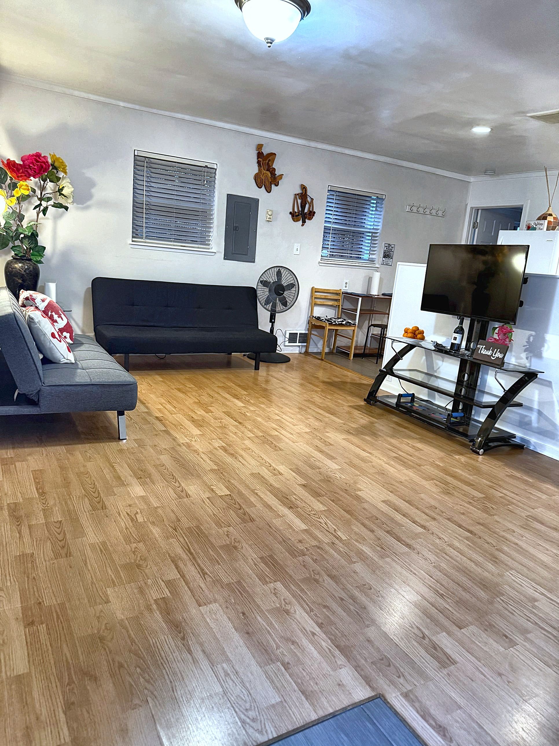 A living room with a sofa, a fan, a treadmill, and a TV.