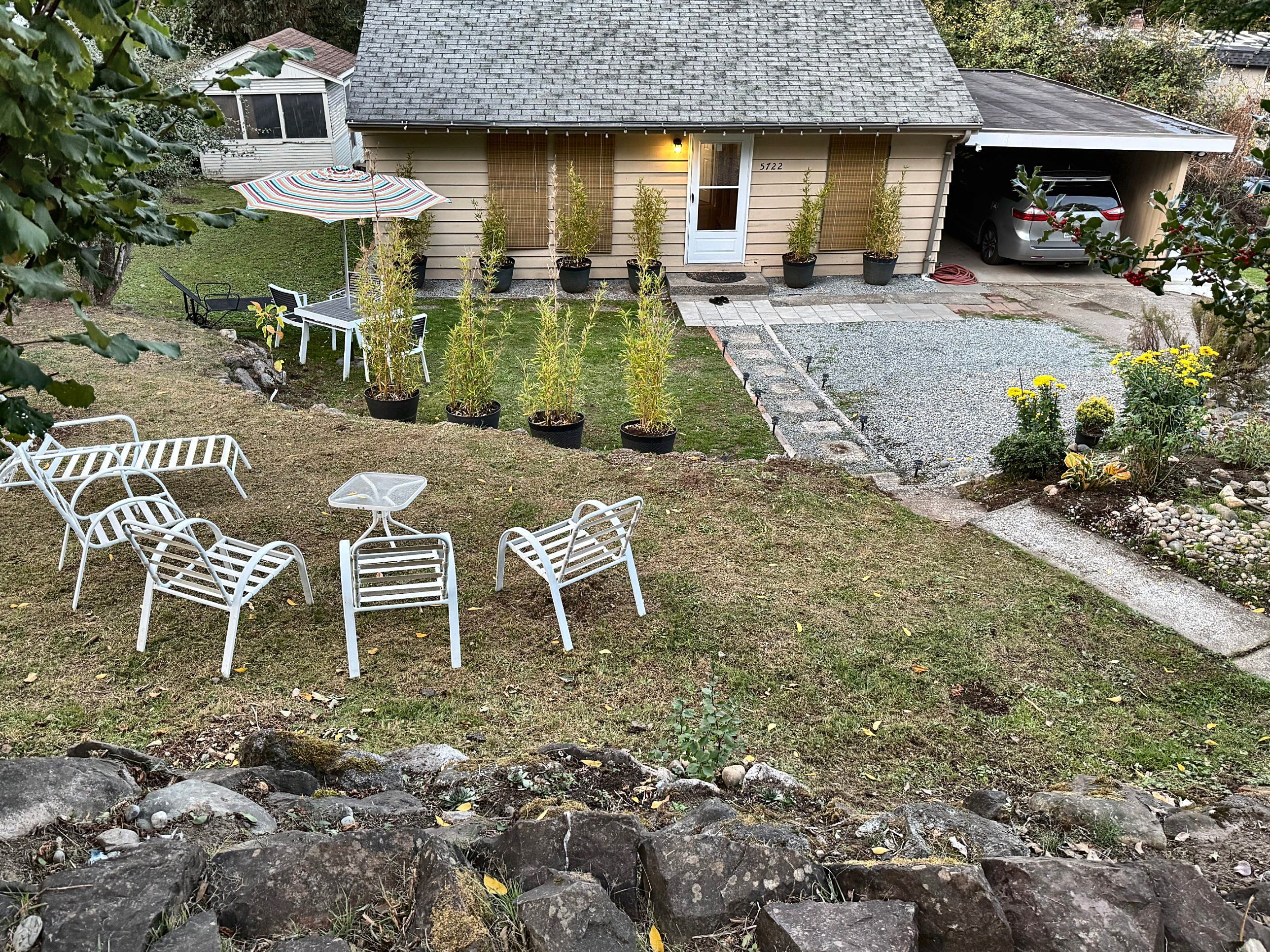 A residential property with a front yard, outdoor seating, and a garage.
