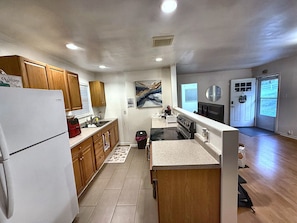 A modern kitchen with wooden cabinets, a refrigerator, a stove, and a sink.