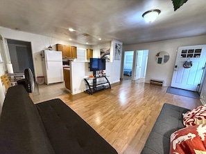 Un espai habitable compacte amb una petita cuina, un sofà, una zona de menjador i una porta que condueix a una altra habitació.