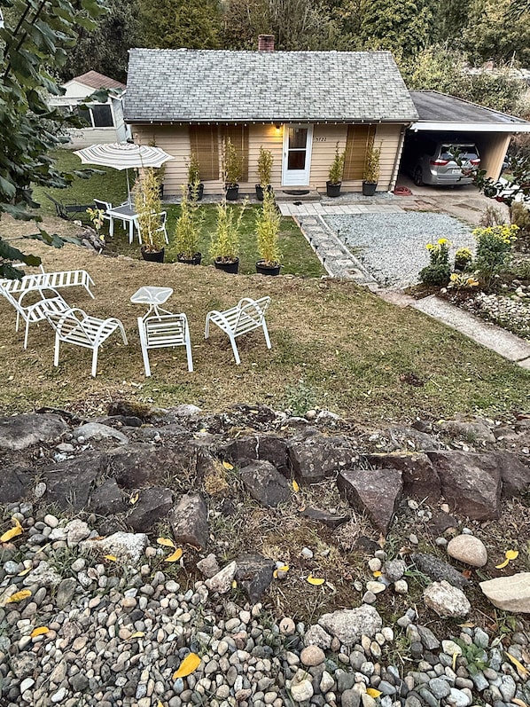 A house with a paved driveway, a garage, and a lawn with outdoor furniture.