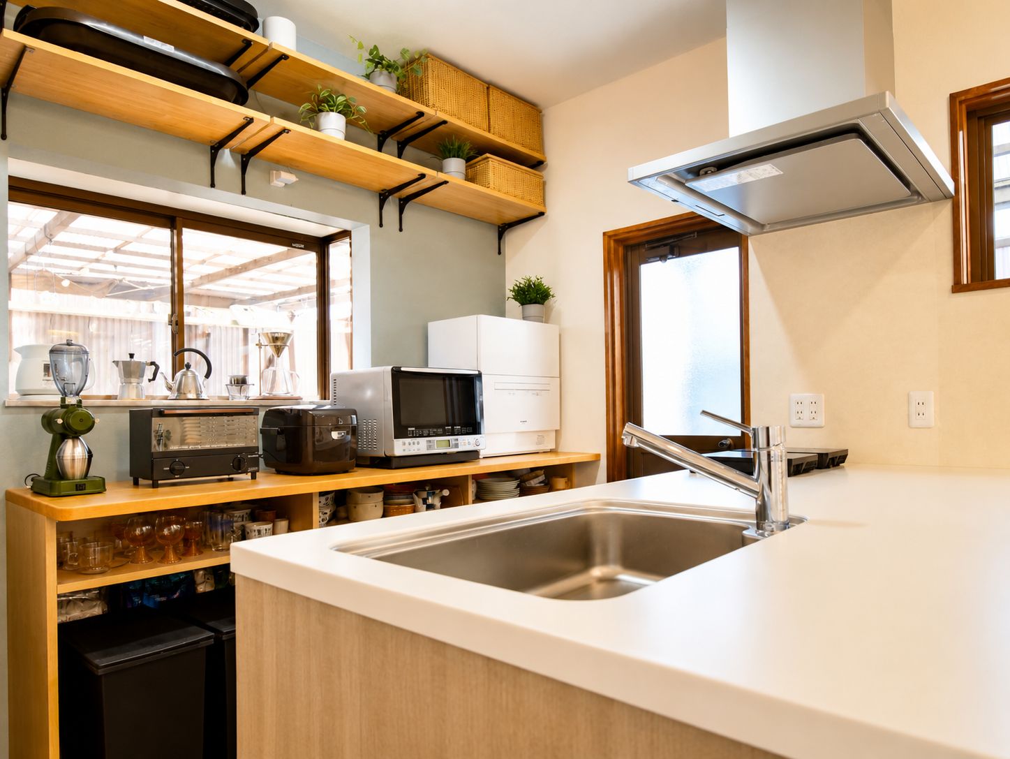 A kitchen with a stainless steel sink, wooden shelves, a microwave, and a coffee maker.