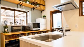 A kitchen with a stainless steel sink, wooden shelves, a microwave, and a coffee maker.