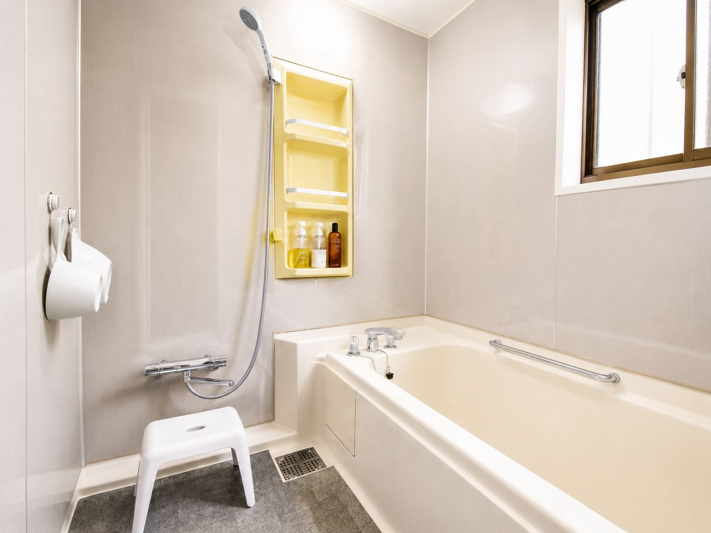 A bathroom with a bathtub, a shower, a step stool, and a medicine cabinet.