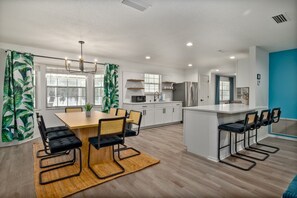Een moderne keuken met witte kasten, een centraal eiland en barstoelen.