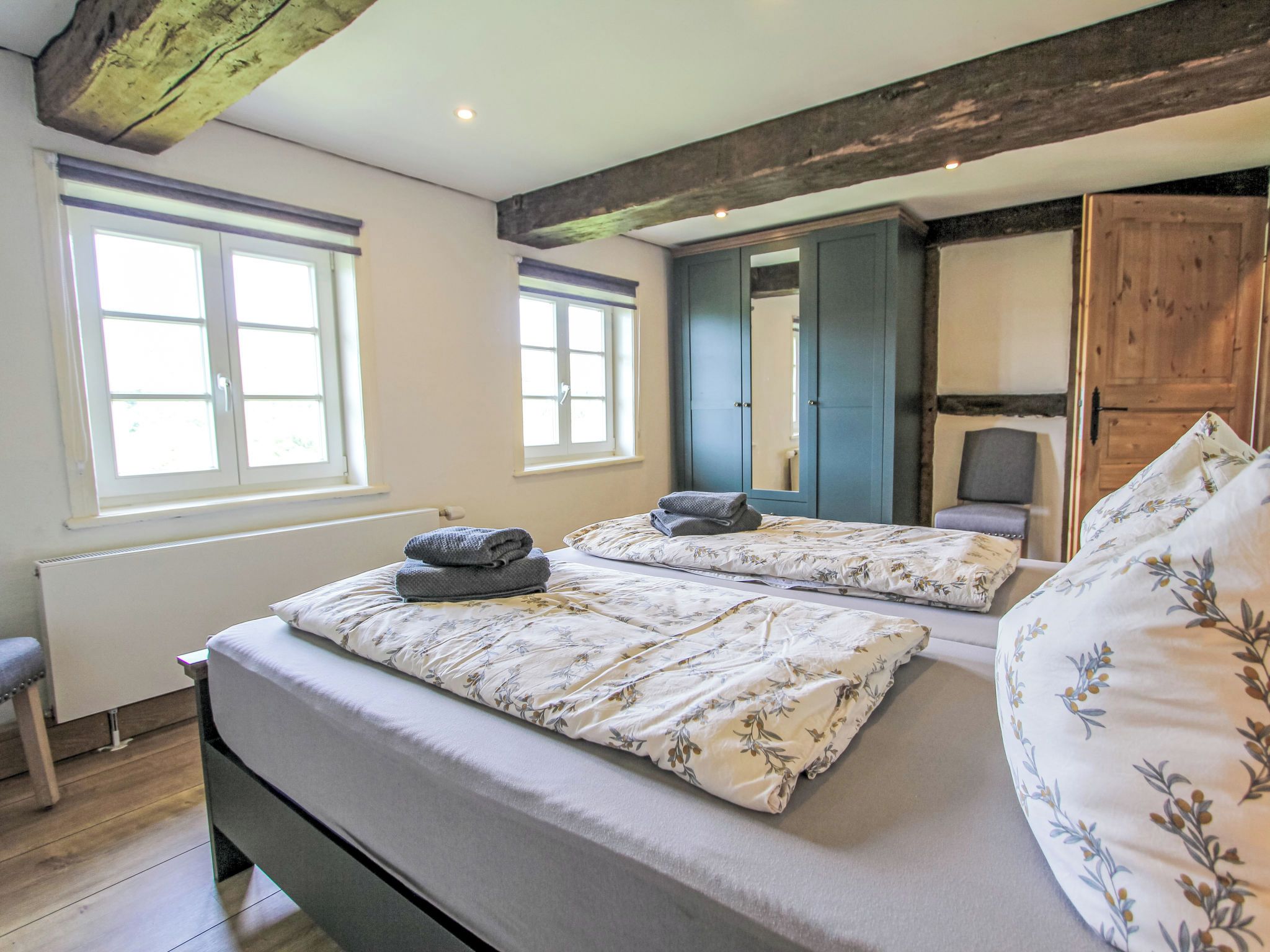 Een slaapkamer met twee bedden, een bankje en een kledingkast.