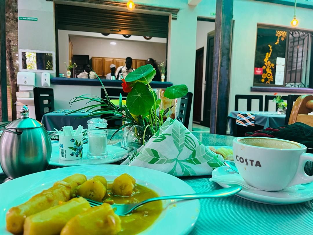 A dining table with a plate of food, a cup labeled 'COSTA,' and a teapot.
