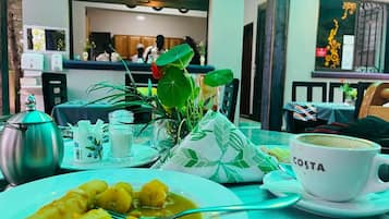 A dining table with a plate of food, a cup labeled 'COSTA,' and a teapot.